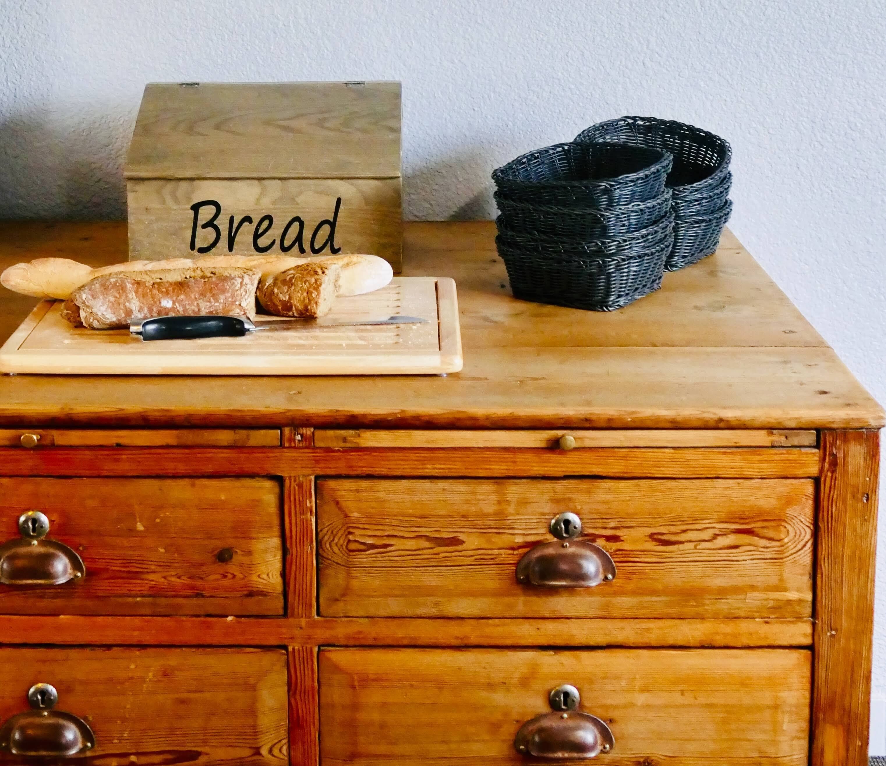 A wooden table with a cutting board, a knife, and a loaf of bread labeled "Bread".