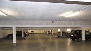 Garagem de estacionamento com vários níveis e diversos carros estacionados sob as colunas.