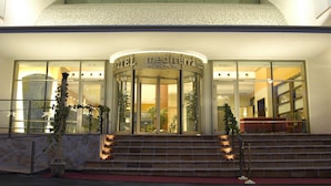 Una entrada de hotel con fachada de vidrio, un conjunto de escaleras que conducen a la entrada y un letrero sobre las puertas que dice "HOTEL mediterrance".