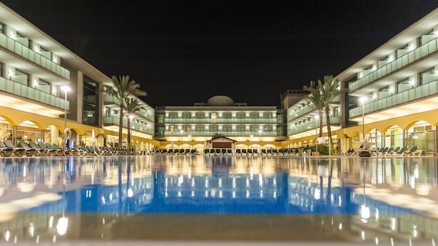Un hotel con una piscina grande, varios pisos y un diseño arquitectónico moderno.