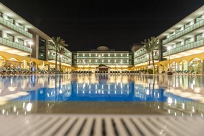 Un hotel con una piscina grande, varios pisos y un diseño arquitectónico moderno.