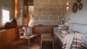 Un salon chaleureux avec un mur en pierre, un canapé, un banc en bois et un fauteuil.