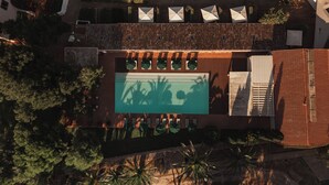 Vue aérienne d’un complexe hôtelier doté d’une piscine, de plusieurs parasols et d’une terrasse en bois.