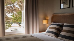 Une chambre d’hôtel avec un lit, une table de chevet avec une lampe, une fenêtre avec des rideaux et une vue sur l’extérieur.