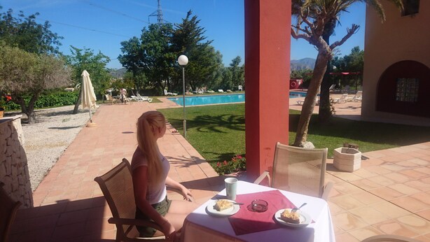 Un patio con una mesa preparada para dos, una piscina al fondo y vistas del paisaje circundante.
