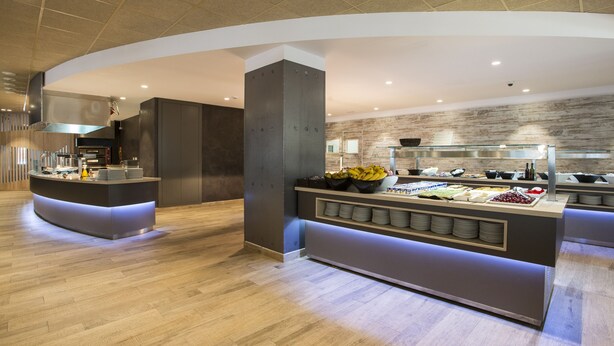 Un'attrezzatura moderna per buffet con un'isola centrale, un angolo cottura e una parete in legno.