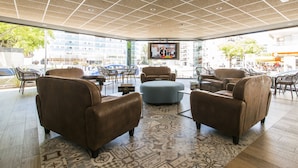Un'area lounge moderna con divani in pelle, un tappeto decorato e uno schermo televisivo.