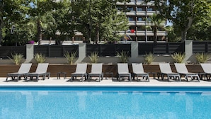 Una piscina con sedie a sdraio e un edificio sullo sfondo.