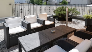 A balcony with wicker furniture, a coffee table, and potted plants. - Hotel Europa (Görlitz)