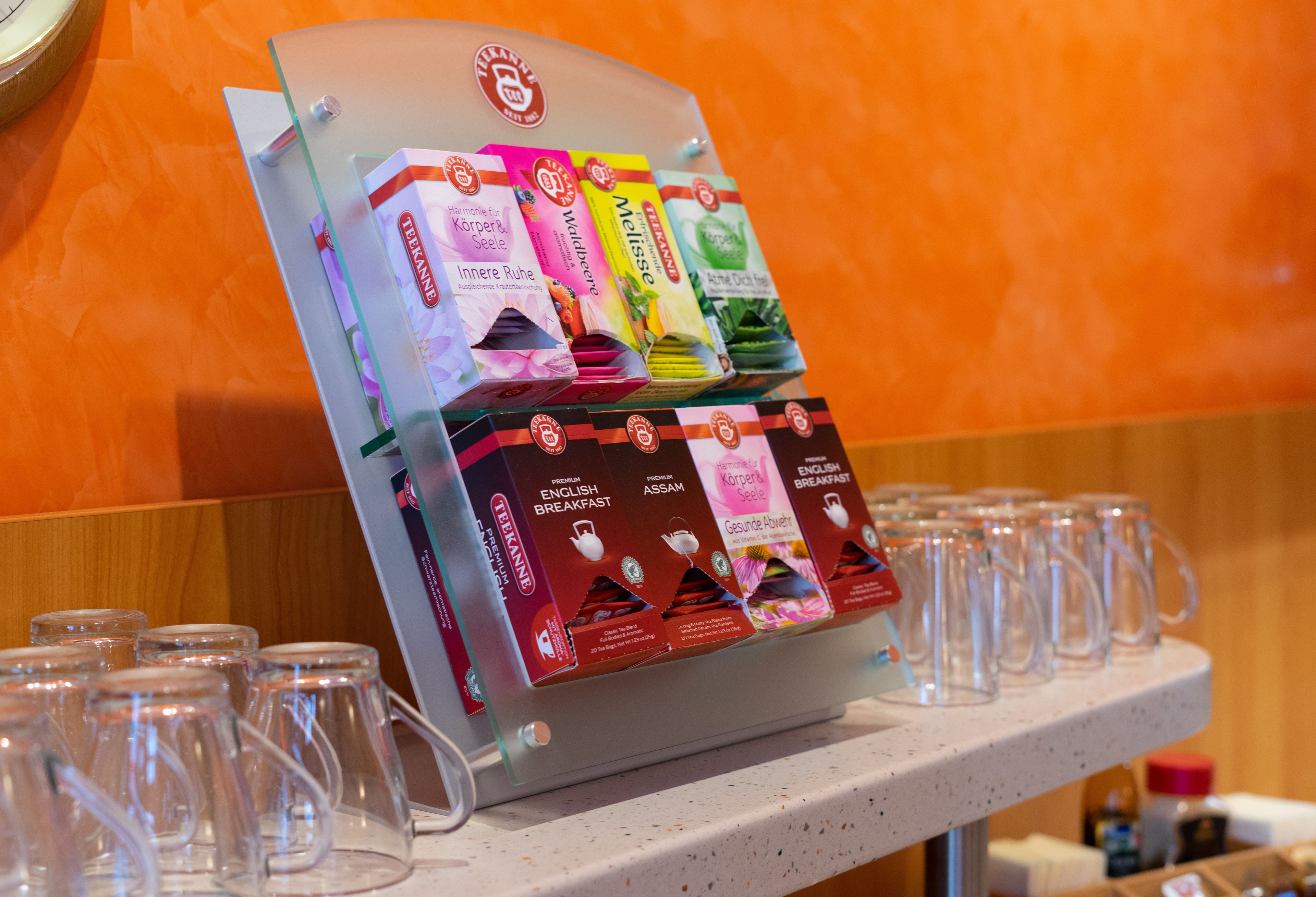 A display of tea boxes and empty glass mugs on a countertop.
