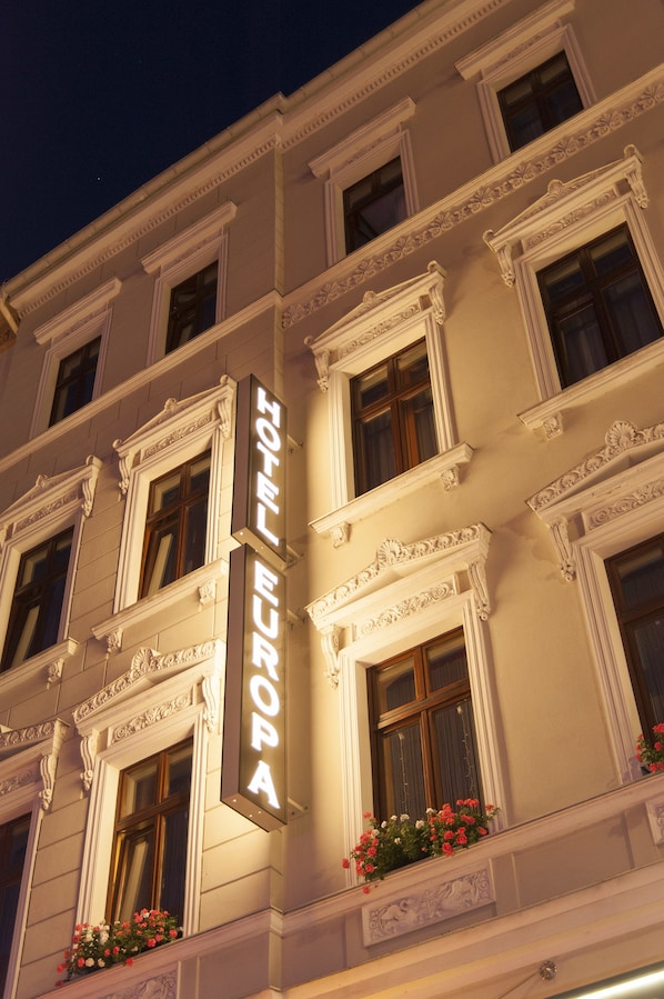 A hotel facade with a prominent sign reading "HOTEL EUROPA," large windows, and decorative moldings.