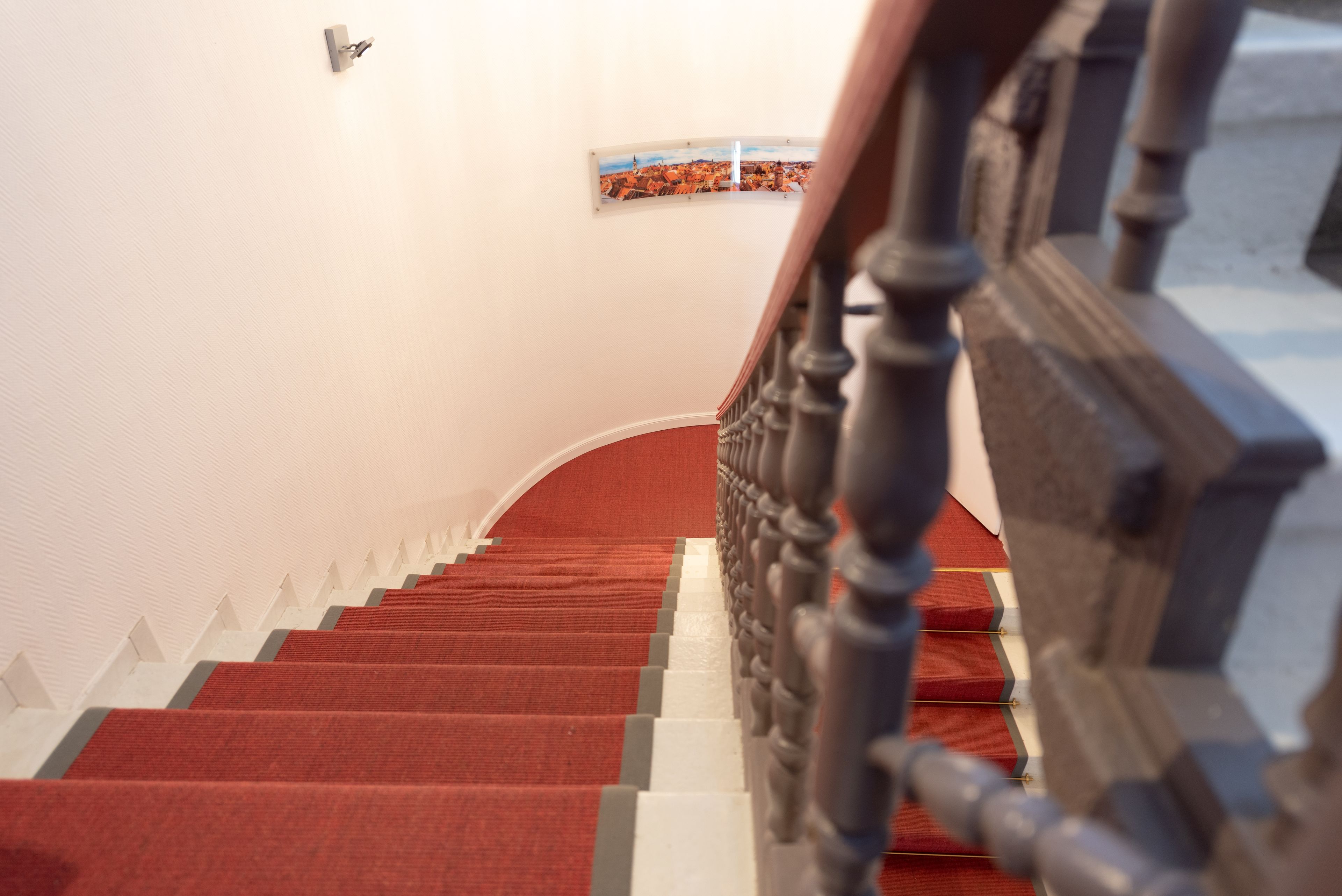 Eine Treppe mit roten Teppichstufen und einem hölzernen Geländer.