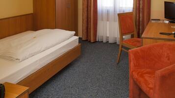 A hotel room with a bed, a desk, a chair, a television, and a wardrobe.
