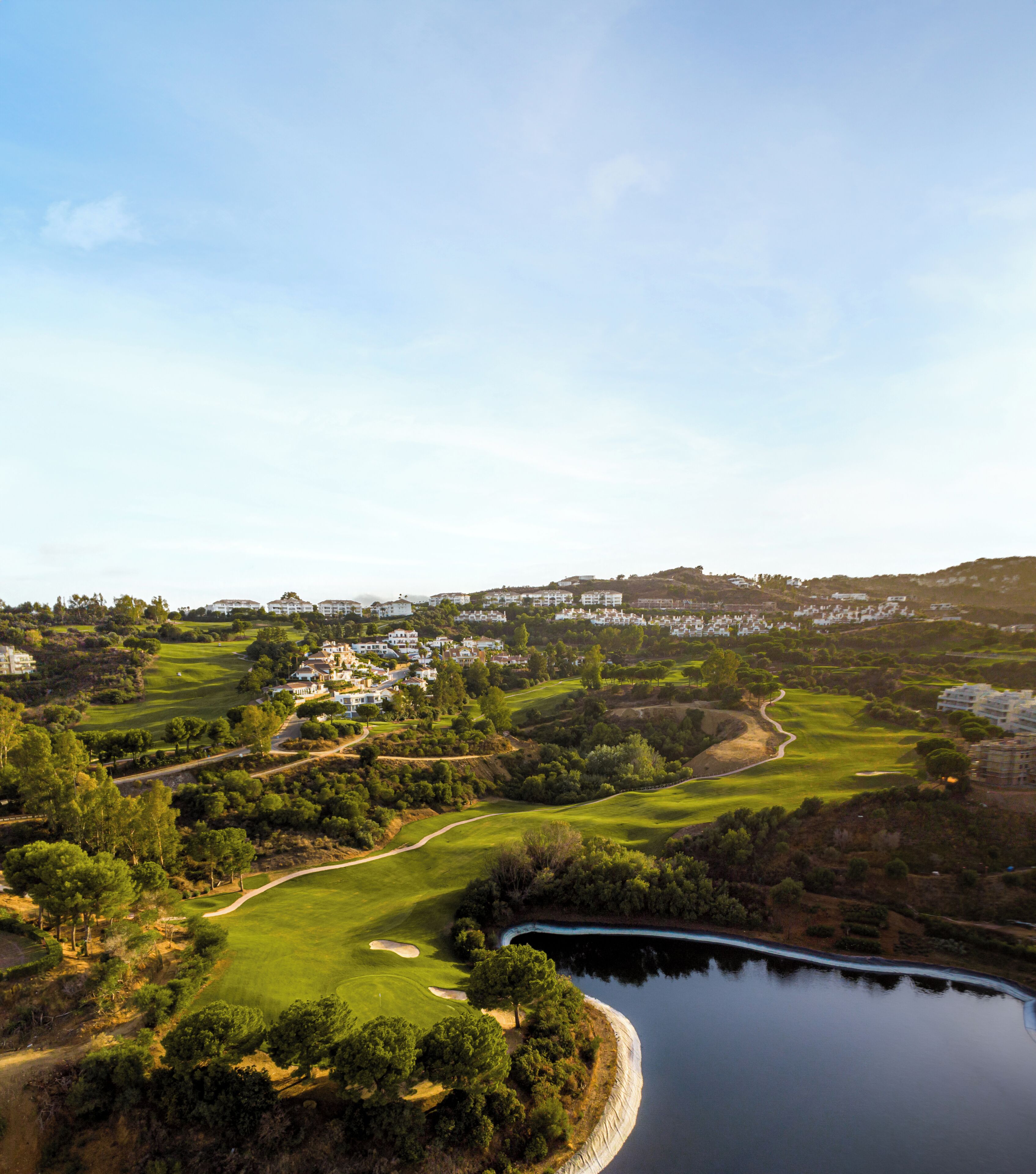 A golf course with a lake, surrounded by residential buildings.