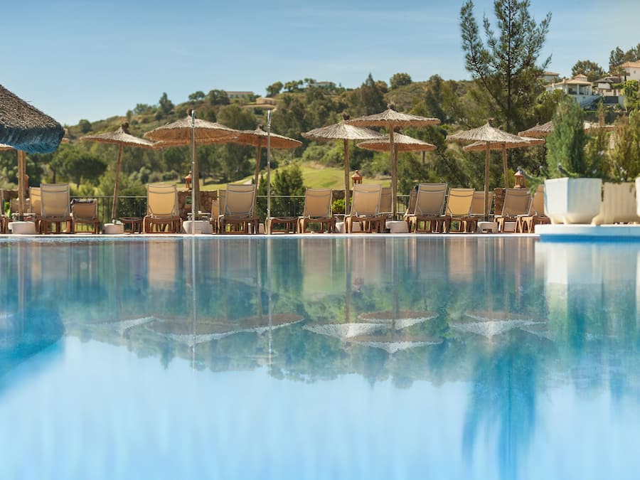 Una piscina techada, una piscina al aire libre, sombrillas
