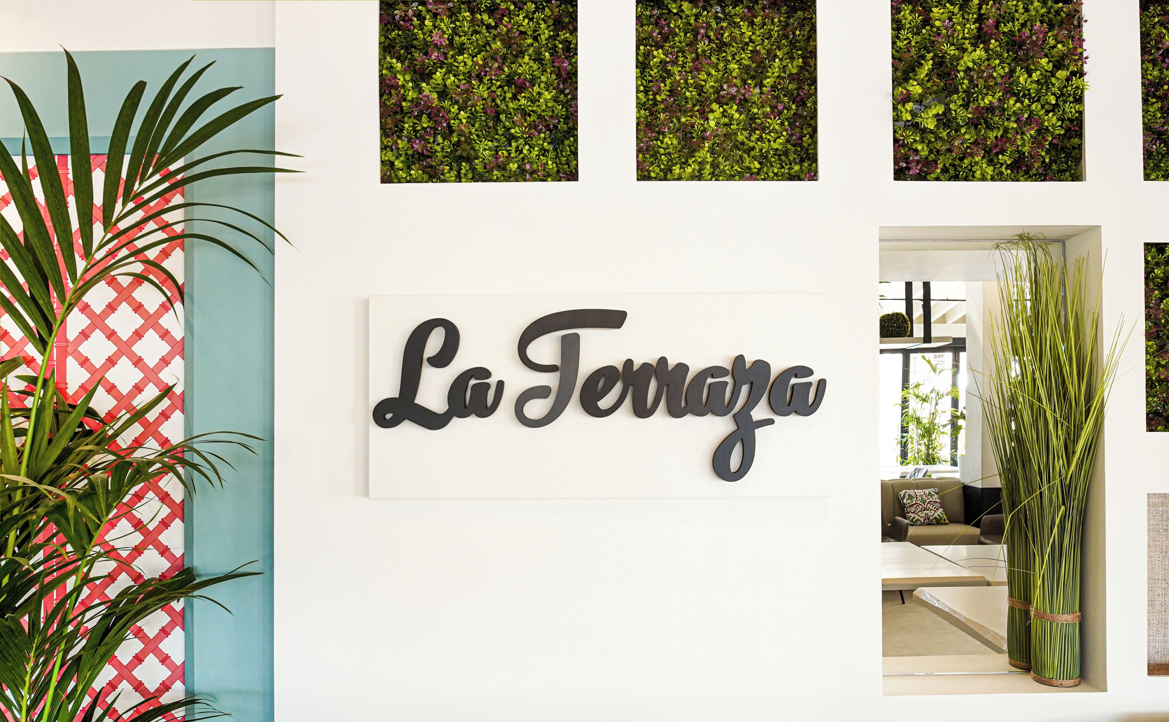 A wall with a sign reading 'La Terrazza,' a red lattice door, and a potted plant.