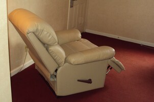 A reclining chair with a footrest, positioned against a wall with a door nearby.