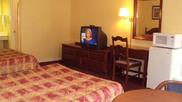 A hotel room with two beds, a television, a desk with a chair, a microwave, and a mirror.