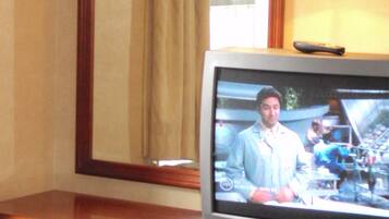 A television on a wooden dresser with a mirror above it.