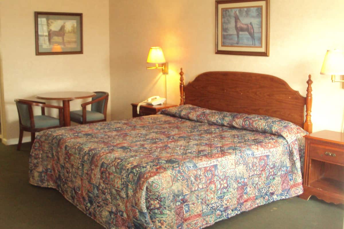Ein Hotelzimmer mit einem großen Bett, einem Nachttisch, einem Sessel und einem Schreibtisch.