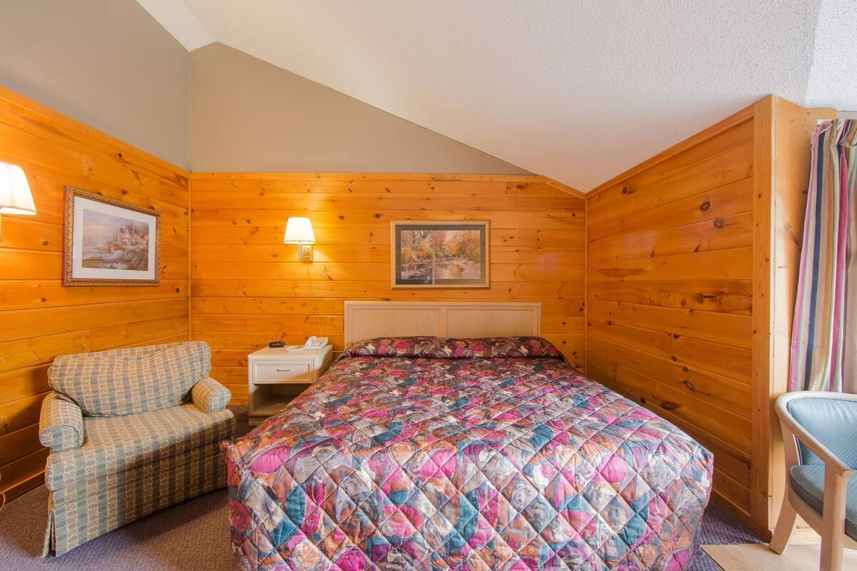 Um quarto aconchegante com uma cama, uma poltrona, uma mesa de cabeceira e uma luminária.