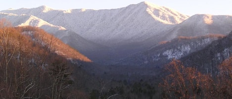 A mountainous landscape with a valley and trees in the foreground.