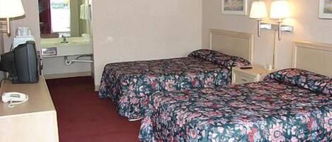 Habitación de hotel con dos camas, un escritorio, una silla, un teléfono y dos lámparas fijadas a la pared.