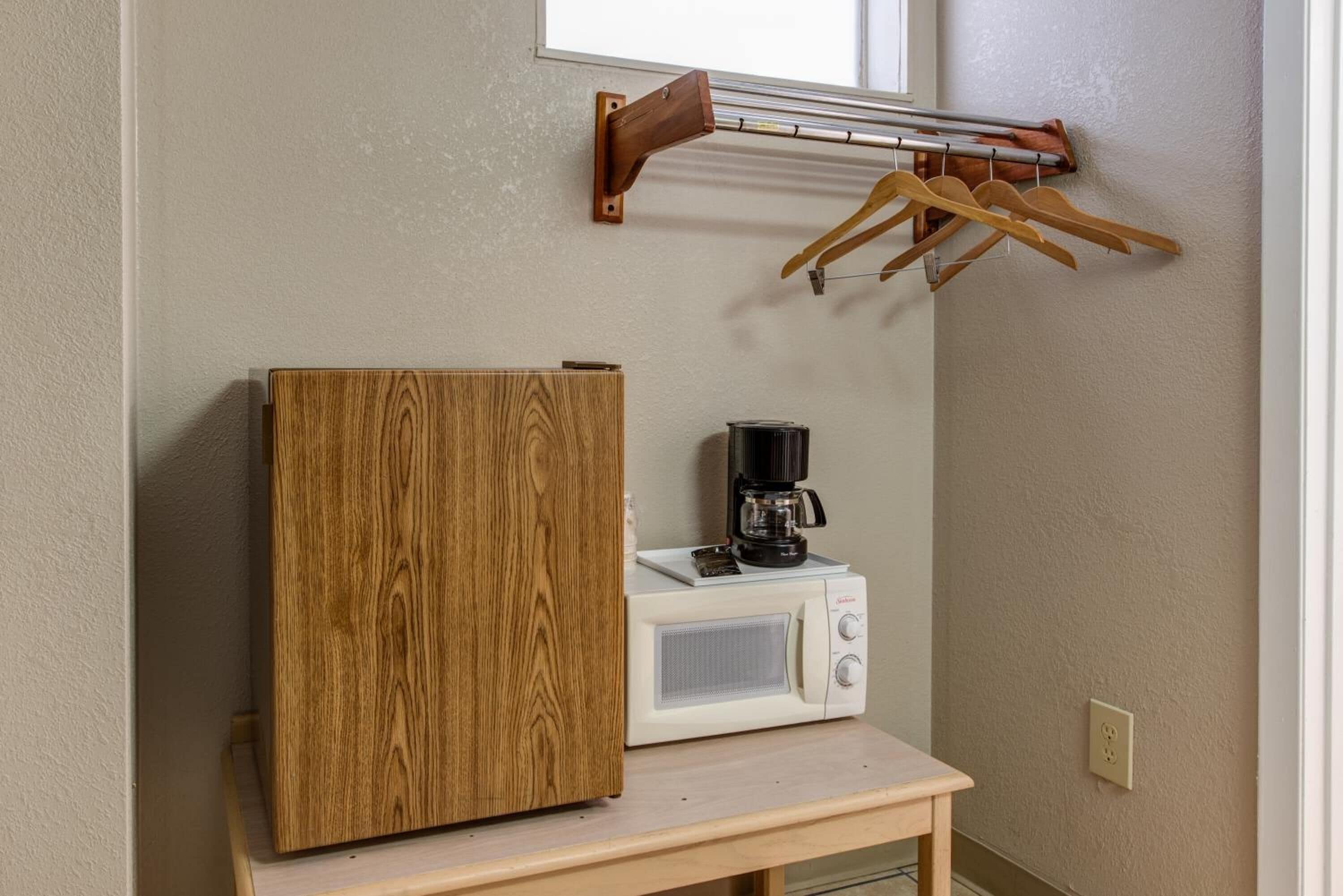 Une petite cuisine équipée d’un four à micro-ondes, d’une machine à café et d’un meuble en bois.