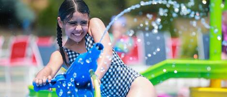 A child playing with a water toy in a pool area.