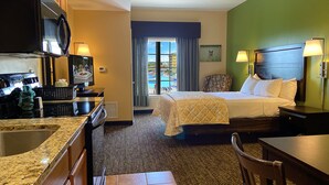 A hotel room with a bed, a desk, a kitchenette, and a view of a pool. - The Resort at Governor's Crossing (Sevierville)