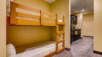 Une chambre avec des lits superposés, et un coin cuisine à l'arrière-plan.