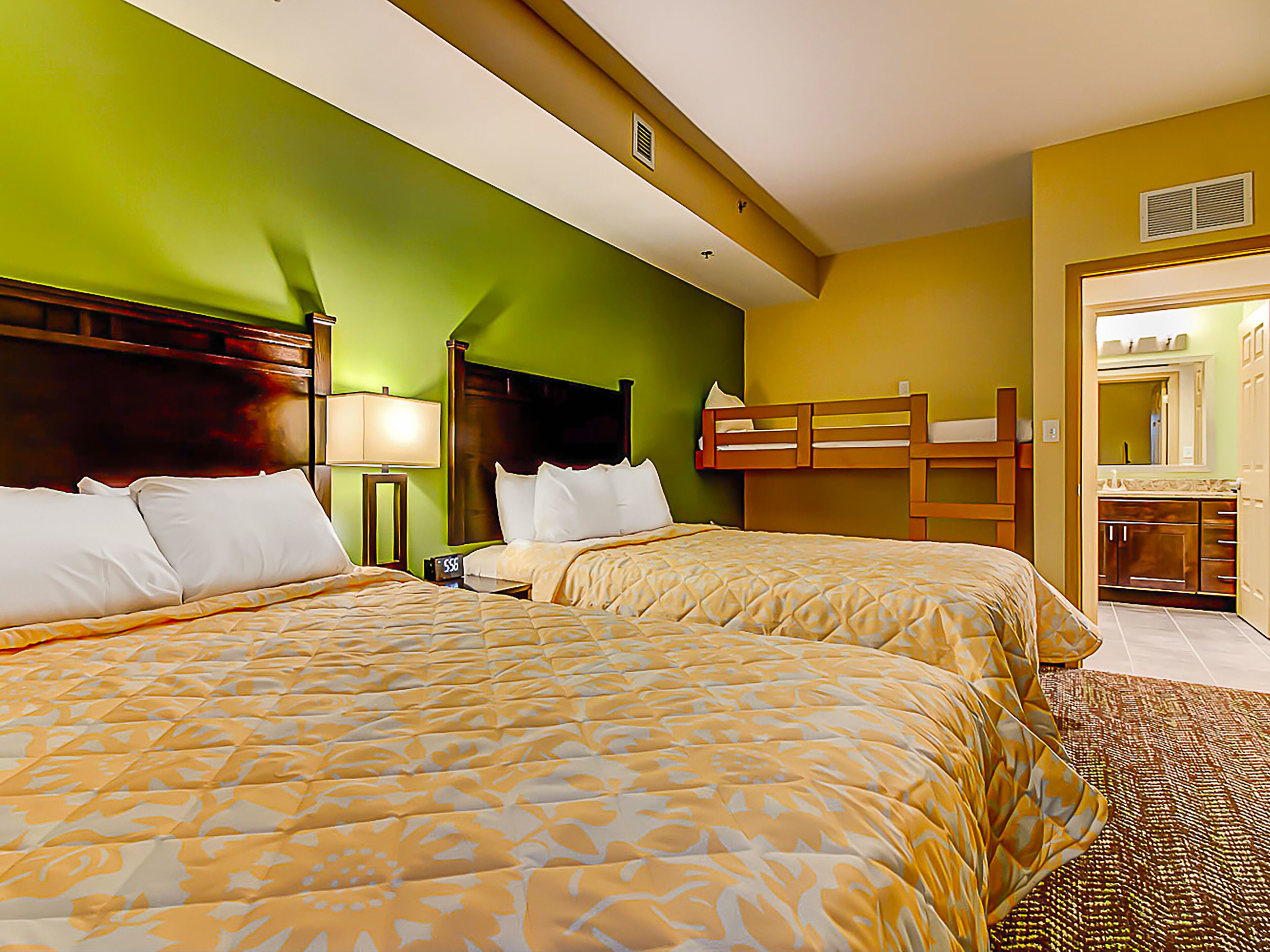 Habitación de hotel con dos camas, una mesita de noche, una lámpara y una cama litera.