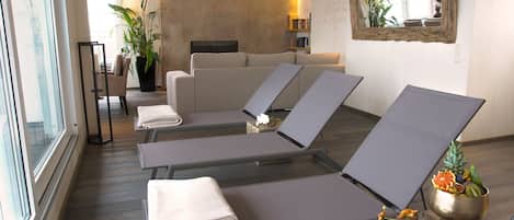 Un cuarto de spa con sillones reclinables, una camilla de masaje y una mesa pequeña con fruta.