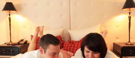 A bed with a tufted headboard, a red and white patterned blanket, and two bedside lamps.