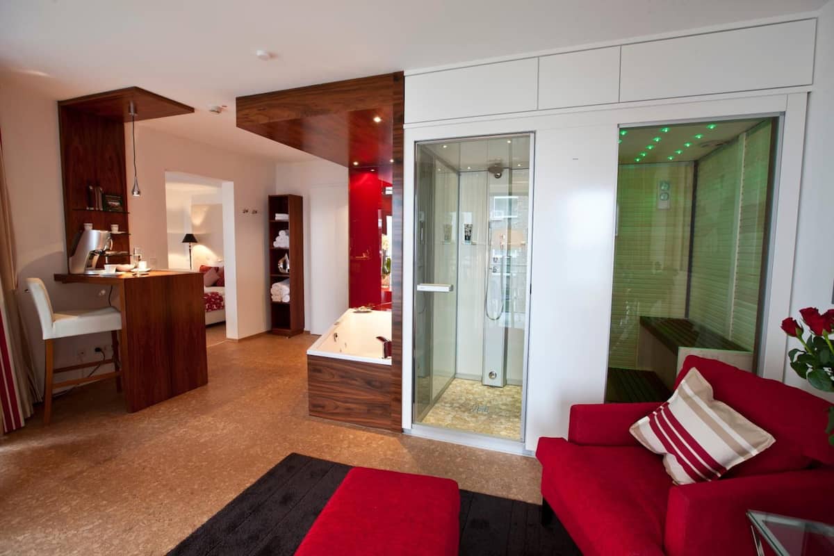 Una sala moderna con un sofá rojo, ducha con cerramiento de vidrio y un armario de madera.