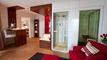 A modern living room with a red sofa, a glass-enclosed shower, and a wooden cabinet.