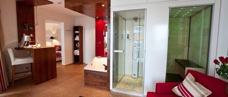 A modern living room with a red sofa, a glass-enclosed shower, and a wooden cabinet.
