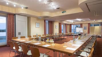 Una sala de conferències amb una taula llarga, cadires i una pantalla de projector.