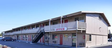A motel with a 'OFFICE' sign, a covered parking area, and a staircase leading to the entrance.
