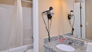 A bathroom with a shower, toilet, sink, and two hair dryers mounted on the wall. - Econo Lodge Kennewick Tri-Cities (Kennewick)