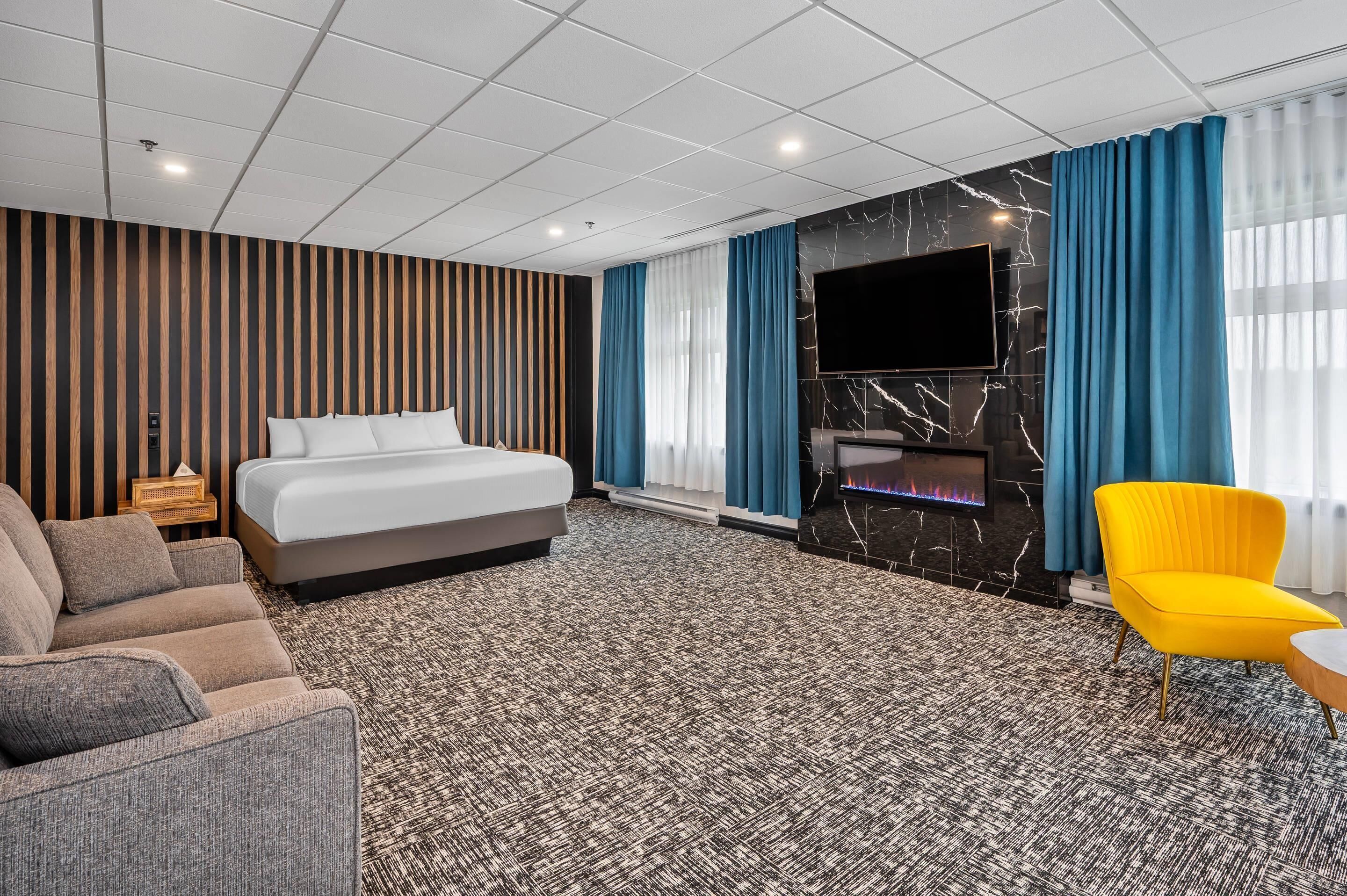 Quarto de hotel com cama, sofá, televisão e lareira.