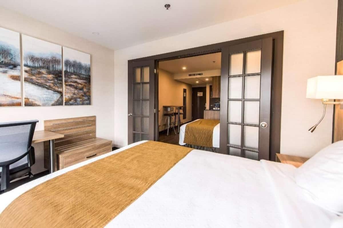 Una camera d'albergo con un letto, una scrivania, una sedia e un quadro appeso al muro.