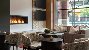 A modern lounge area with a fireplace, comfortable seating, and a large window offering a view of the outside.