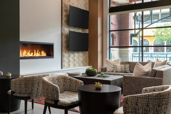 A modern lounge area with a fireplace, comfortable seating, and a large window offering a view of the outside.