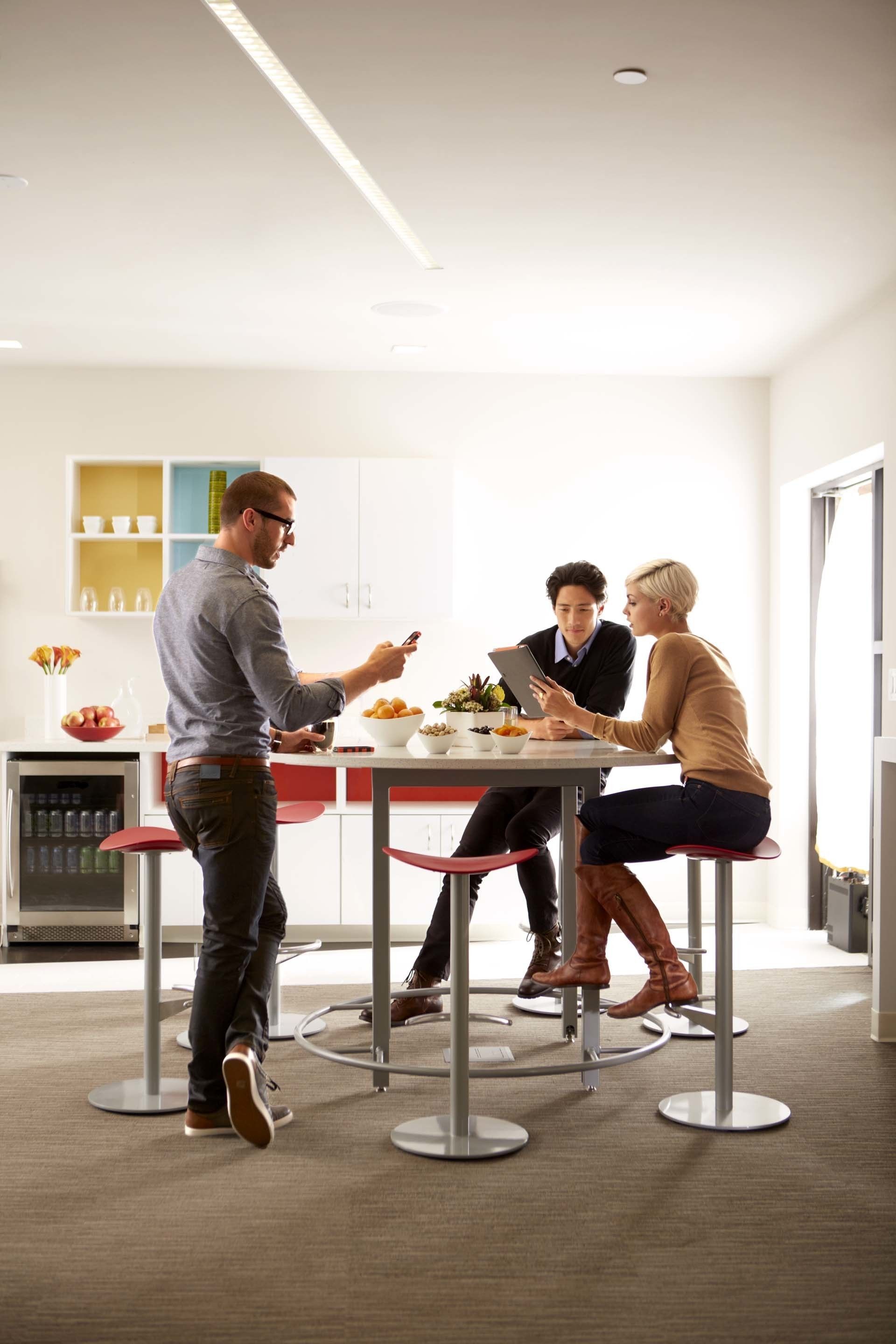 A modern kitchen with a central island, a refrigerator, and a dining area with stools.