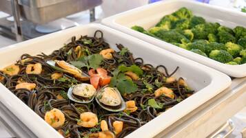 A buffet with seafood pasta and broccoli.
