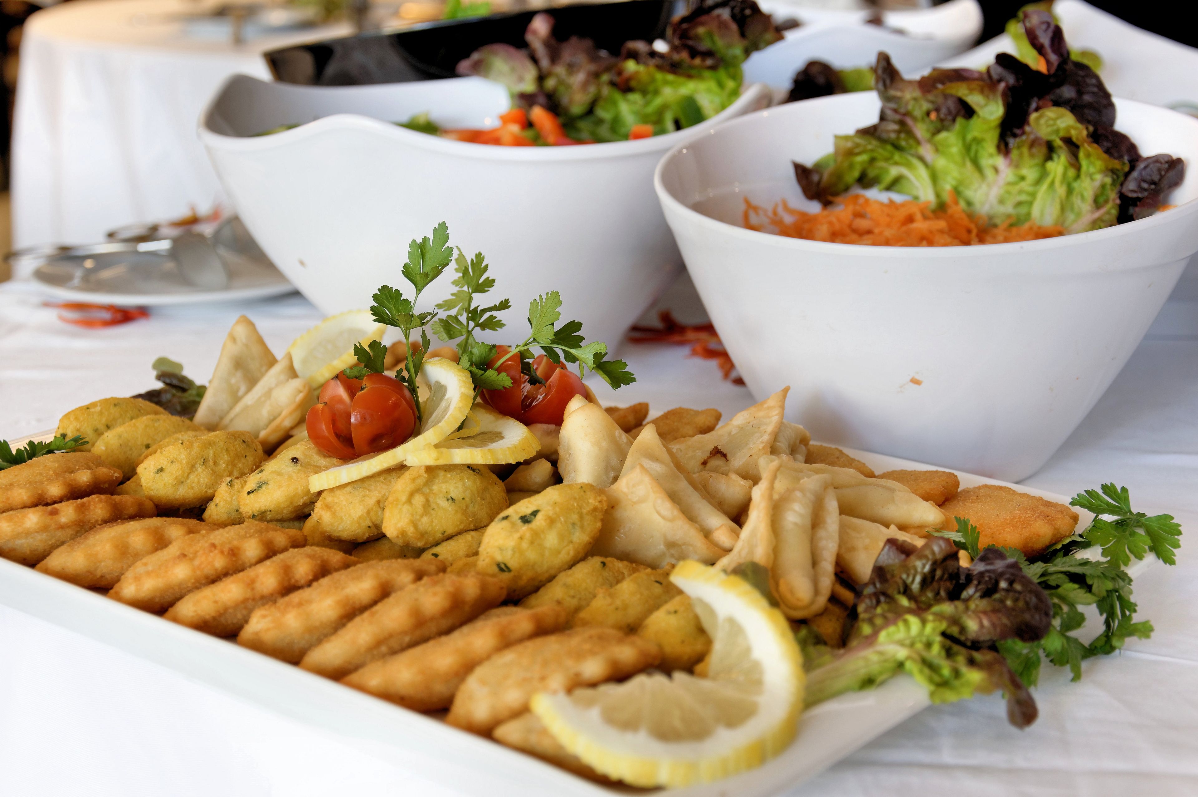 Una mesa con diversos platos, incluyendo panes empanizados, papas fritas y ensaladas.