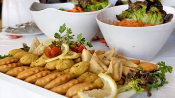 Una mesa con diversos platos, incluyendo panes empanizados, papas fritas y ensaladas.