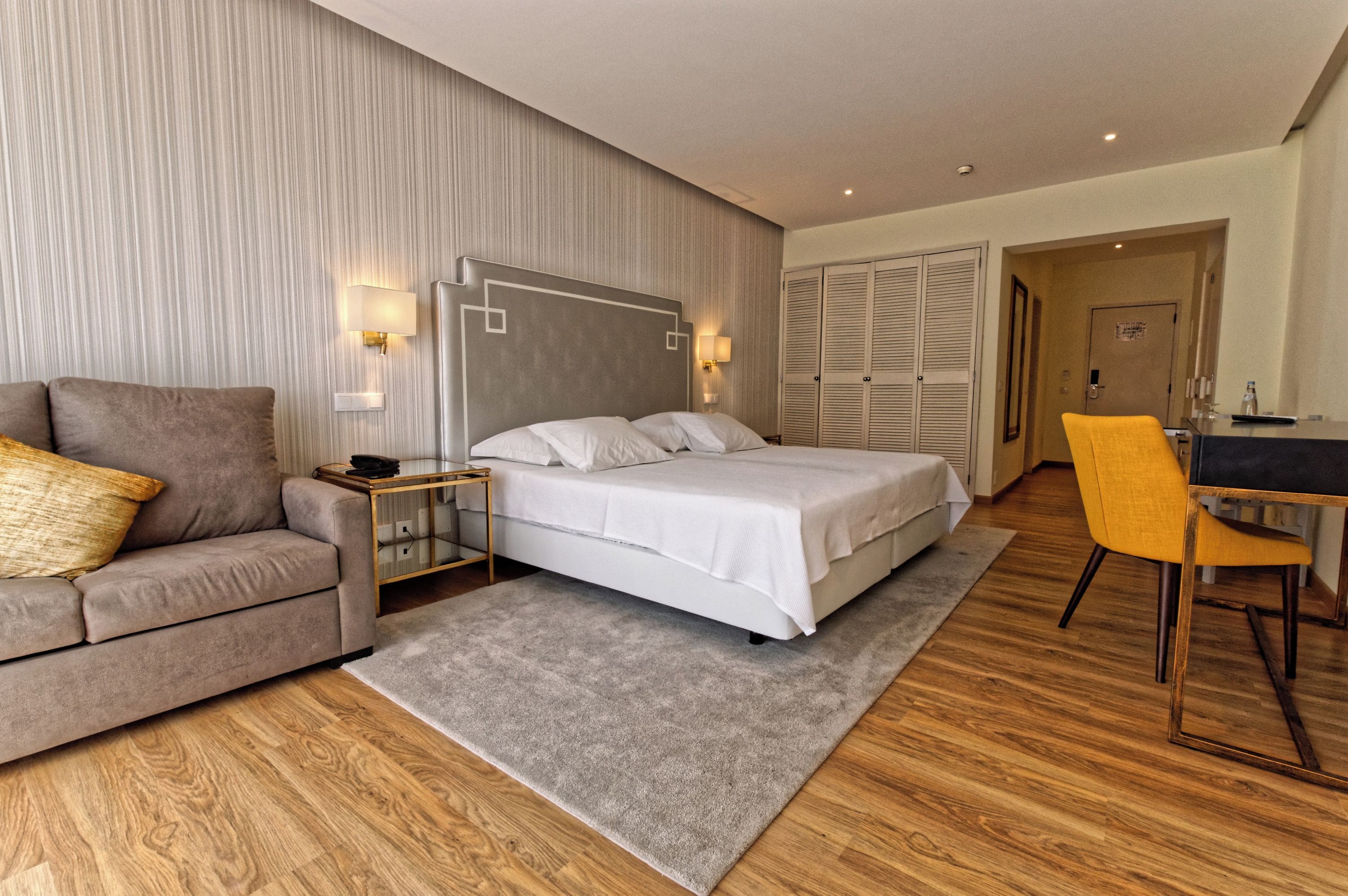 Una habitación de hotel con una cama, un sofá, un escritorio y una silla.