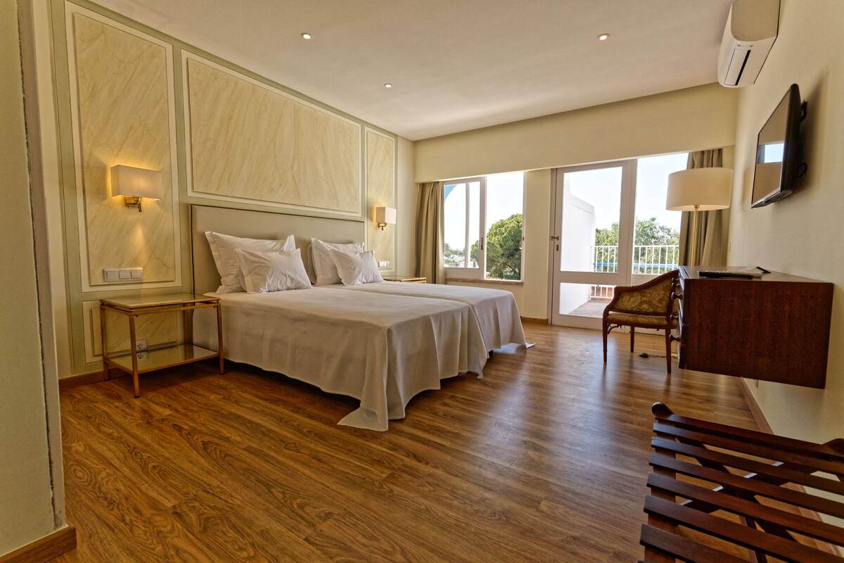 A hotel room with a large bed, two bedside tables, a chair, and a TV.